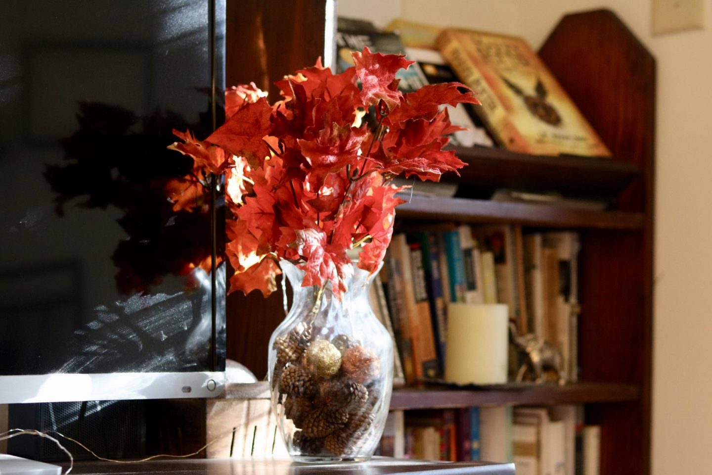 Vase of pinecones and red leaves