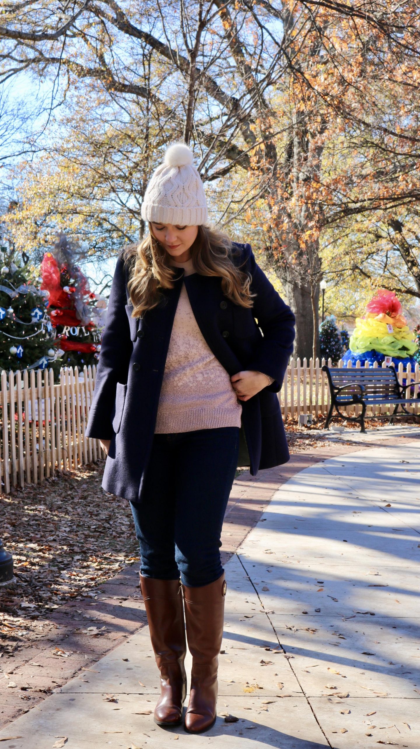 Katie in navy coat and bobble hat looking down