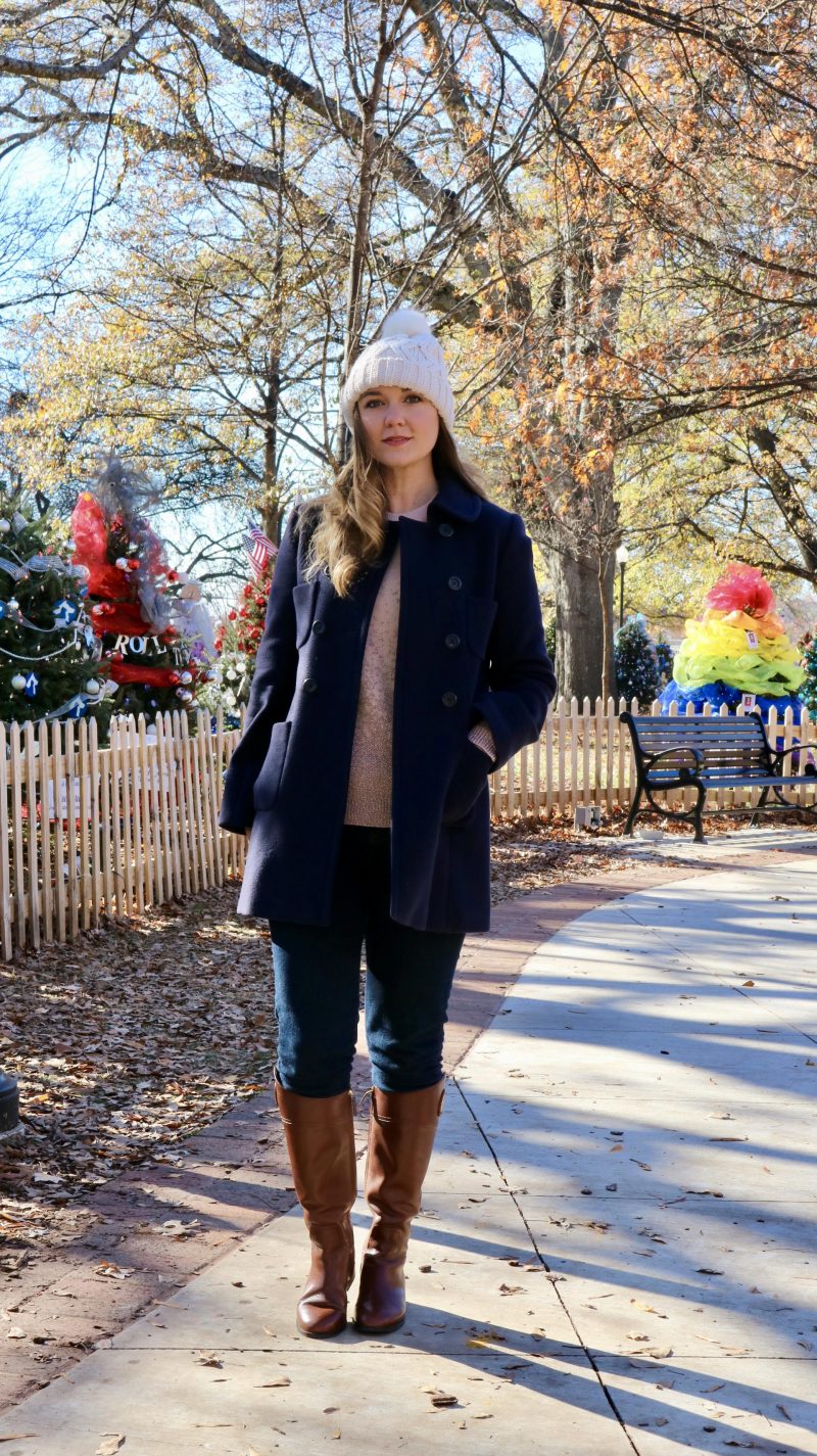 Katie in navy coat and white bobble hat looking at camera